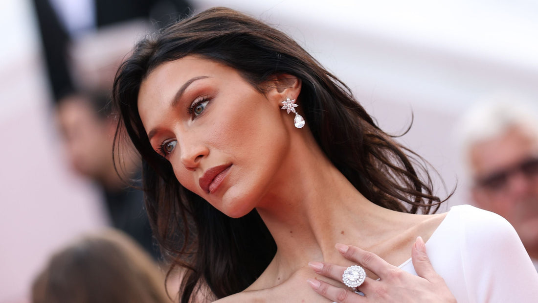Bella Hadid wearing a vintage-style oval-cut diamond engagement ring with bezel halo and 18k yellow gold band, sparking engagement rumors and setting celebrity jewelry trends in Paris.