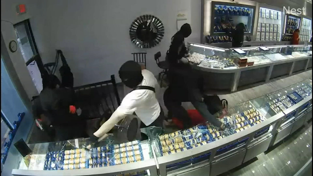 Security camera still of masked thieves stealing luxury watches from a jewelry store, highlighting watch theft risk in high-end retail.