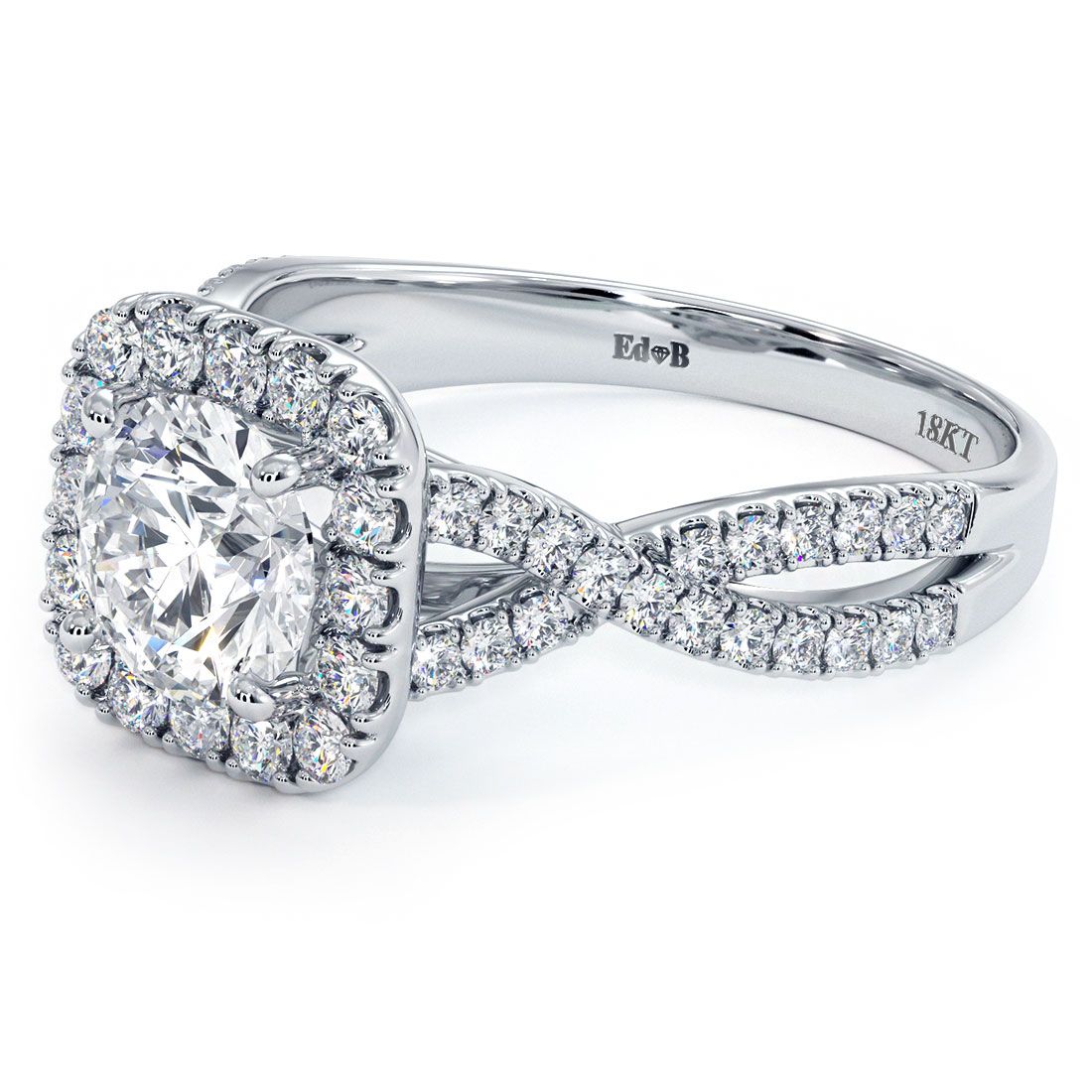 Angled close-up of Cushion Halo Infinity Twist Diamond Engagement Ring Setting in 18k white gold for a 1.50ct round center. Featuring 0.53ctw G color SI1 clarity round side stones in a romantic halo with twisting pavé shoulders. Exclusive design by Global Sky Diamonds, 44W 47th St Booth GF-10 in the Diamond District NYC. View and shop bridal jewelry at globalskydiamond.com