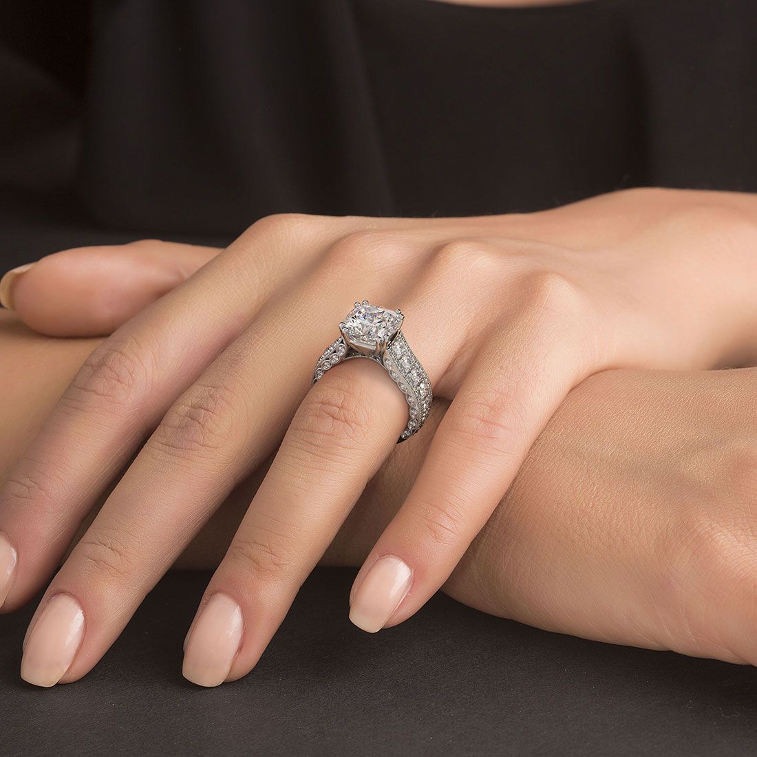 Full-hand view of luxurious vintage-style cushion cut engagement ring with milgrain edges, split shank, and sparkling G color SI1 side diamonds in 18K white gold. Signature design from Global Sky Diamond, located at 44 W 47th St Booth GF-10, Diamond District NYC. See more at www.globalskydiamond.com.