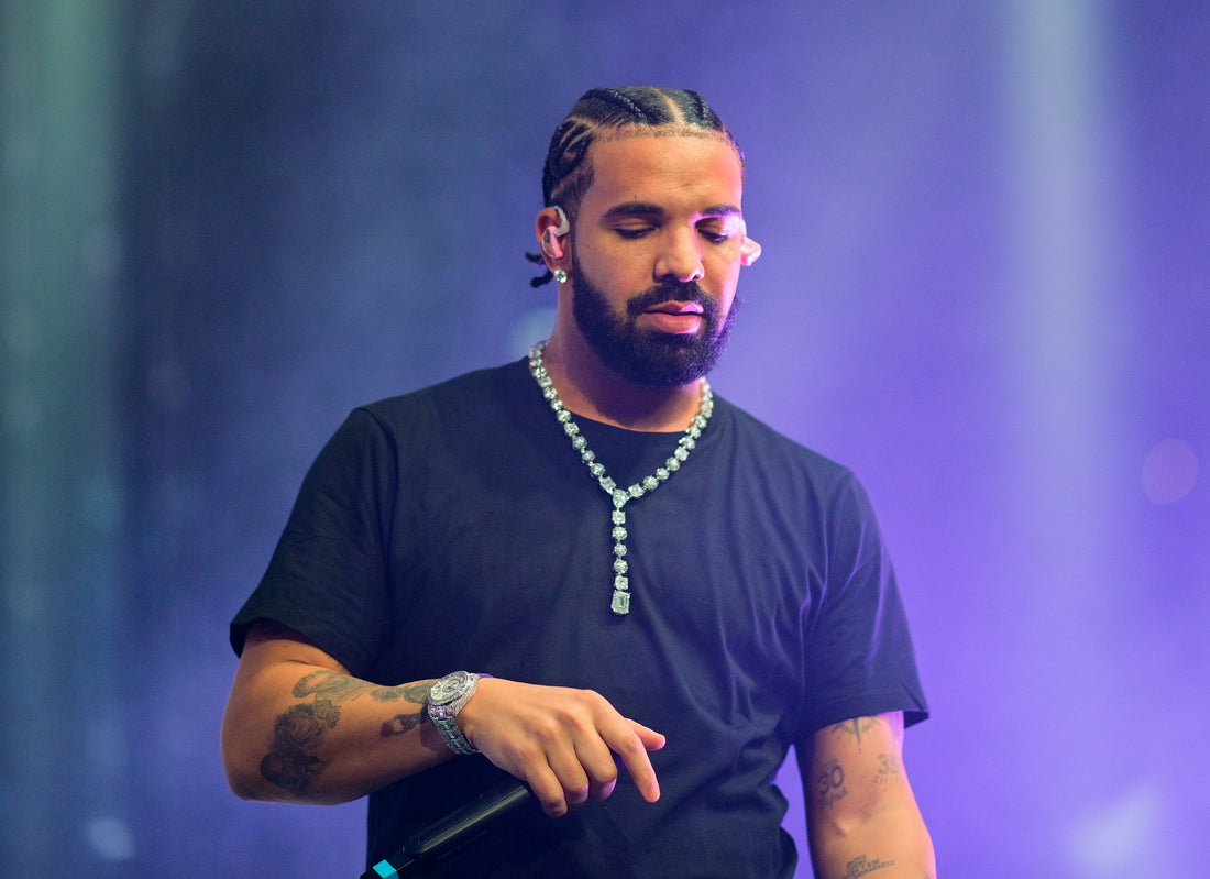 Drake wearing an iced-out Cuban link chain on stage, representing celebrity hip hop jewelry trends and luxury gold chains from the Diamond District